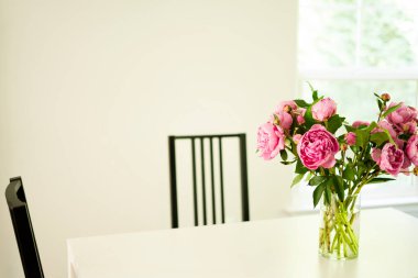 Beyaz bir masa, vazo ve sandalyelerle dolu.