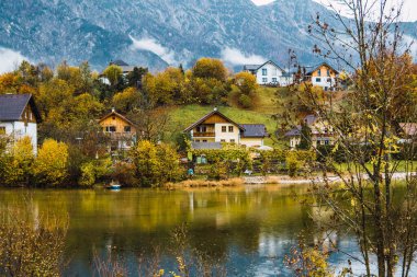 Ağaçlar ve dağlarla çevrili bir gölün önündeki evler