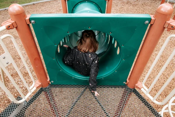 Young girl going down a slide at a park