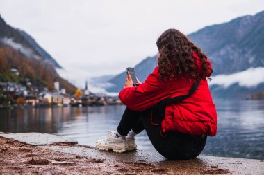 Kadın gölün kenarında oturuyor Hallstatt köyünde