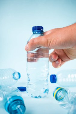 El, su şişesi ve diğer plastik şişeleri alıyor.