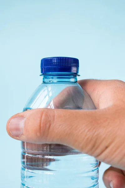 Mano Tomando Botella Agua Plástico Sobre Fondo Azul —  Fotos de Stock