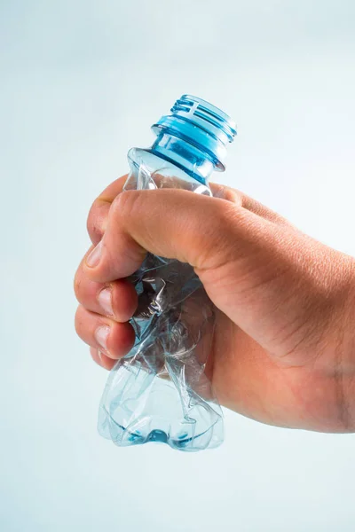 Χέρι Απογύμνωση Ένα Πλαστικό Μπουκάλι Μπλε Φόντο — Φωτογραφία Αρχείου