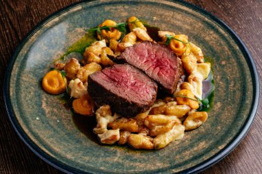 Yanında sos ve meze ile orta pişmiş biftek.