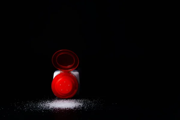Närbild Röd Saltskakare Med Spillt Salt Ett Svart Bord — Stockfoto