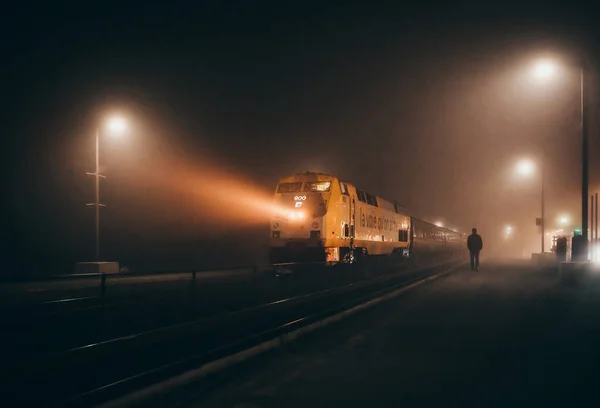霧深い夜に静かな鉄道駅に到着する旅客列車 — ストック写真