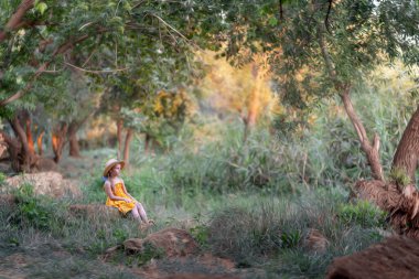 Parkta oturan şapkalı kız.