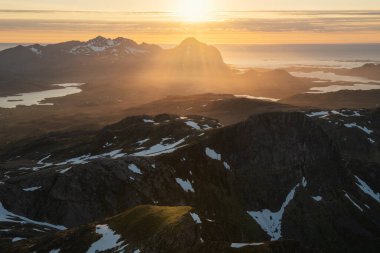 Gece yarısı güneşi Norveç, Lofoten Adaları, Vestvgy 'nin dağ manzarasının üzerinde parlıyor.  