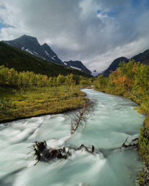 Steindalsbreen 'den gelen renkli buzul nehri Steindalen, Lyngen Alpleri, Troms ve Finnmark Norveç' te sonbahar manzarası boyunca akar.