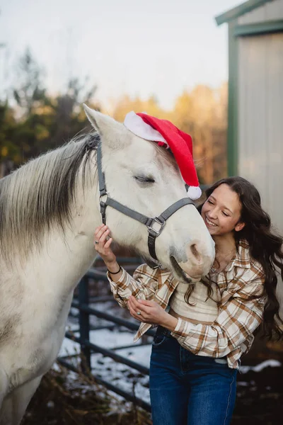 ホワイト馬ともにサンタ帽子と笑顔ティーン女の子 — ストック写真