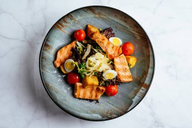 Kızarmış somon salatası, sebze ve otlar.