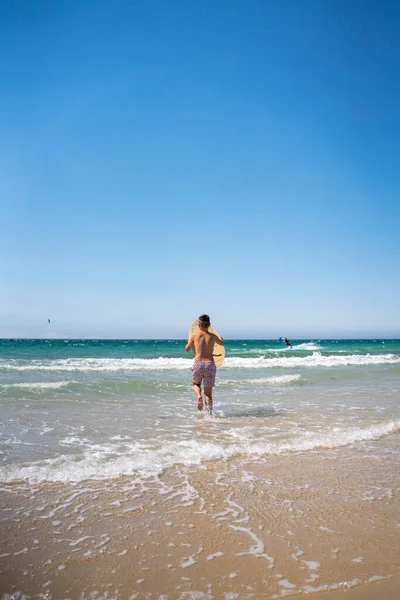 กชายผมด าโต บกระดานด าของเขาบนชายหาดในภาคใต ของสเปน — ภาพถ่ายสต็อก