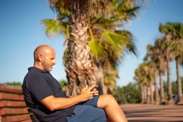 Łysy Człowiek Mówi Używa Swojego Smartfona Tropikalnym Kraju Palmami — Zdjęcie stockowe
