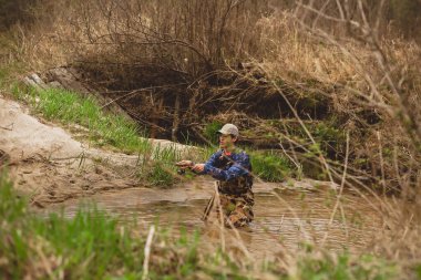 Genç adam dere suyuna olta atıyor.