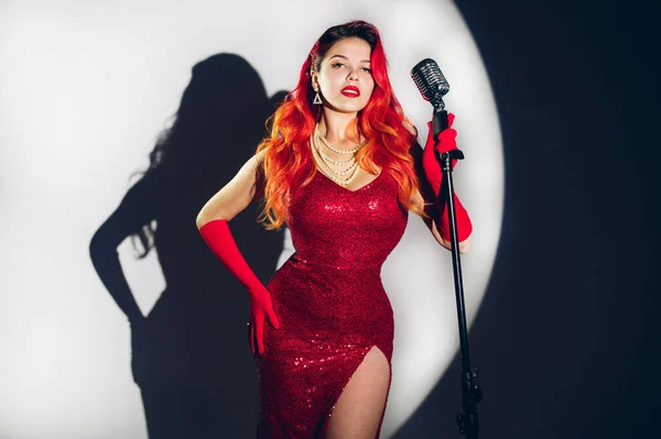 Kırmızı Parlak Elbiseli Kızıl Saçlı Mikrofonlu Güzel Bir Kadın — Stok fotoğraf