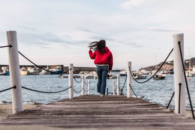 Denizin önündeki tahta iskelede yürüyen kadın.