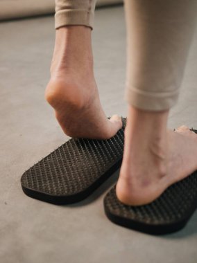 Keskin metal çivilerle tahta tahtada duran kadın sadhu yoga tahtası.