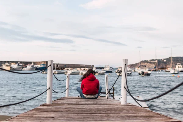 海の前の木製の桟橋に座っている女性は — ストック写真