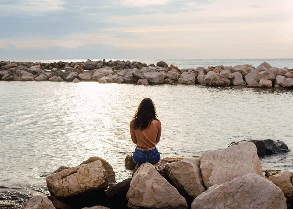 日没時に海の前の石の上の女性は — ストック写真