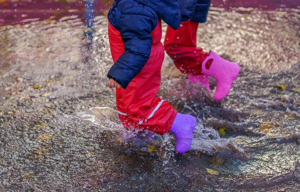 Två Barn Som Går Genom Vattenpöl Med Sina Stövlar Regnig — Stockfoto