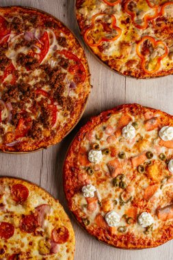 Tahta bir masada pizza, birkaç çeşit.