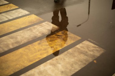 Pedestrian crossing across road in rain.