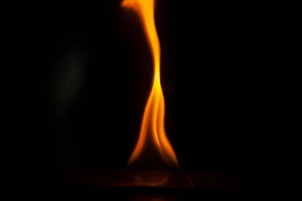 Flames in dark. One flame on black background. Ignition details. Fire burns yellow. Evaporation of alcohol.