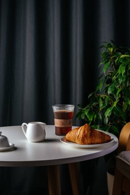 Kahve ve kruvasan, oturma odasındaki beyaz bir masada.