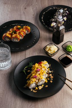 Masadaki tabaklarda çeşitli suşi çeşitleri var. Soya sosu, wasabi. Asya restoranı menüsü