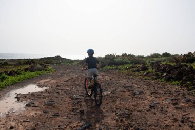 The boy rides a bicycle off-road. coast of the atlantic ocean