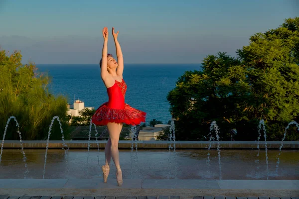 young ballet dancer with red outfit dancing outdoors with her red outfit