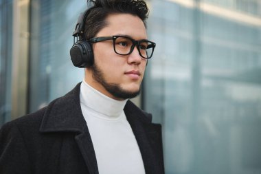 Kulaklık takmış Asyalı bir iş adamı. Yakın çekim, açık hava.