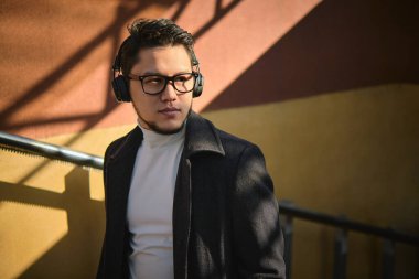 Asyalı bir adam alt geçitten kalkıp güneşe bakıyor.