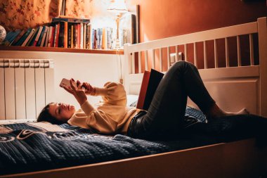 woman reading a book lying in bed at night