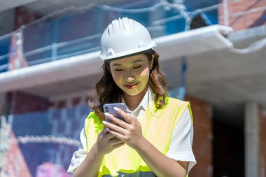 female architect looking at blueprints on her smartphone