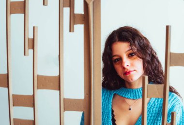 woman in blue dress between bars against white background
