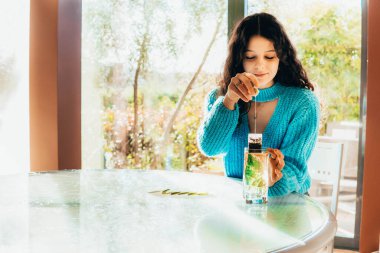 single woman preparing a tea in the kitchen against bamboo