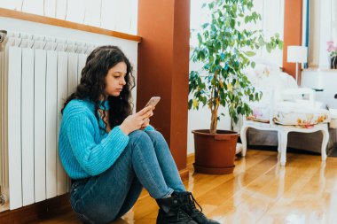 sad woman dressed in blue sitting in the living room of her house