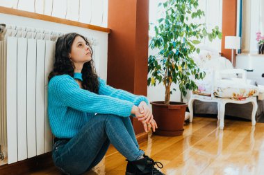 sad woman dressed in blue sitting in the living room of her house
