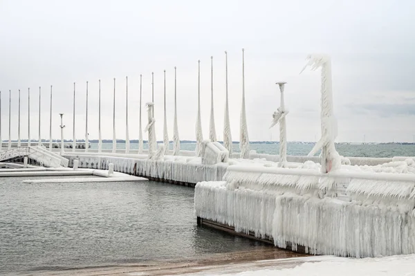 Ice covered poles on pier on Lake Ontario after a winter storm.