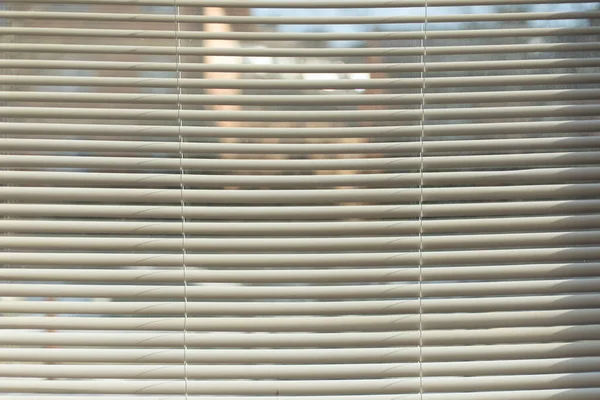 Blinds on window. White blinds. Interior details. Texture made of plastic slats. Horizontal lines.