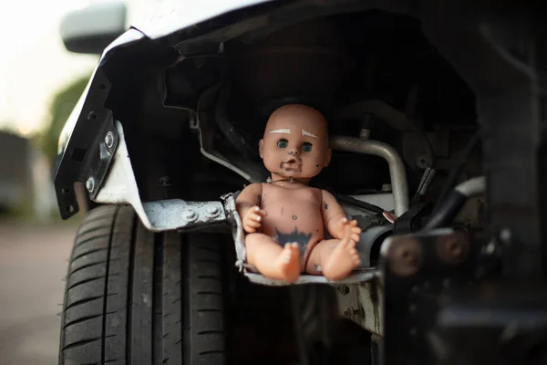 Baby doll on car wheel. Tuning Machine. Doll inside machine mechanism. Baby sits in transport.