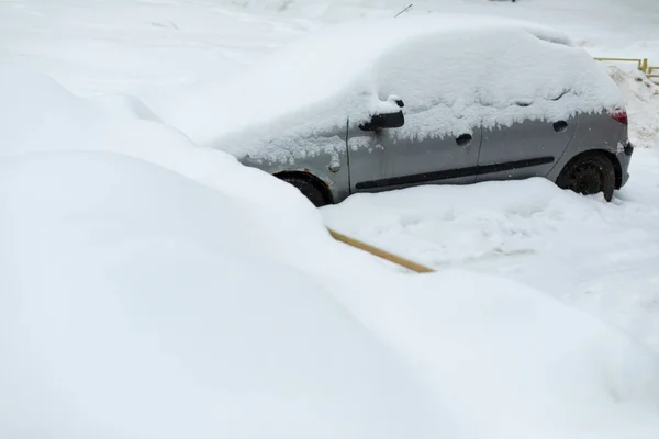 Car in winter in parking lot. Car is parked in snow. Snowdrifts in parking lot. After snowstorm.