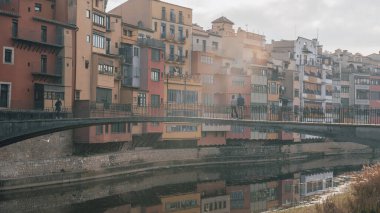 Girona, Spain : january 2023 : Colorful houses reflected in the Onyar river, in Girona, Catalonia, Spain. Church of Sant Feliu and Cathedral of Santa Mara in the background in 2023. 