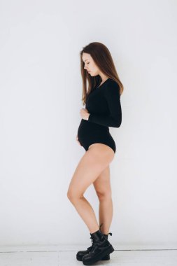 young pregnant blonde on the background of a white wall