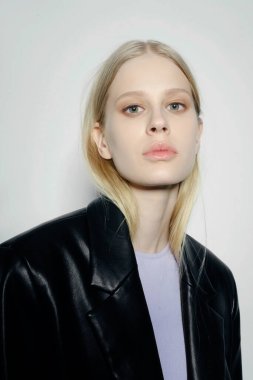 Doğal görünüş. Güzel model kadın. Gri arka planda poz veren genç ve güzel bir model ile model test portresi. Siyah ceketli sarışın bir kadın. Doğal makyaj.