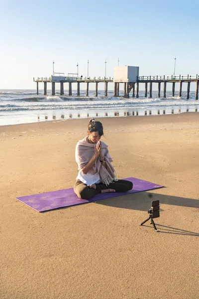 スリム女性ヨガインストラクターは 携帯電話のカメラでオンラインヨガのトレーニングを提供します ヨガとソーシャルネットワークのための瞑想 — ストック写真