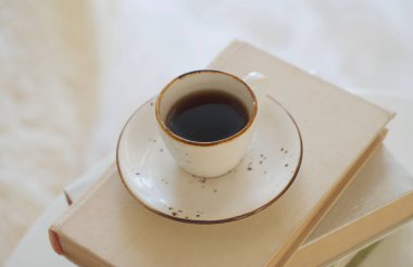 A cup of black coffee stands on a stack of books. High angle view