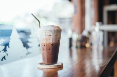 Iced cocoa glass on wooden table with outdoor street view