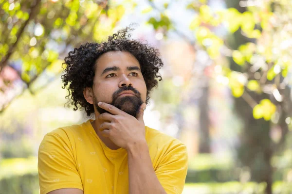 portrait of a Mexican man thinking with afro and beard thinking pose